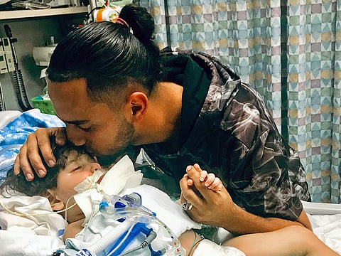 Ali Hassan kissing his dying 2-year-old son Abdullah in a Sacramento hospital.