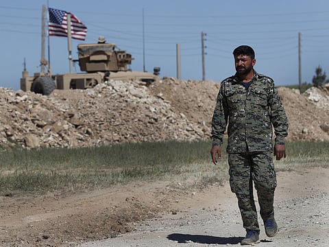 In this April 4, 2018 file photo, a U.S-backed Syrian Manbij Military Council soldier passes a U.S. position near the tense front line with Turkish-backed fighters, in Manbij, north Syria.