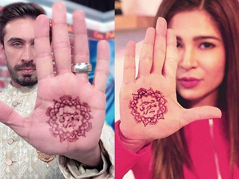 Actors Ali Rehman Khan (left) and Ayesha Omar with the words ‘jahez khori bandh karo’ (stop asking for dowry) written on their hands.