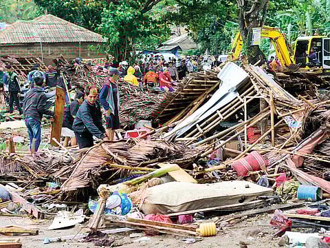 Residents inspect a house destroyed by the tsunami in Carita.