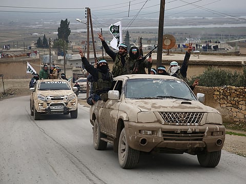 Turkish-backed Syrian fighters raise their weapons as they arrive in the border rebel-held town of Qirata after leaving their barracks in the town of Jarabulus on their way to the northern town of Manbij, on December 25, 2018.