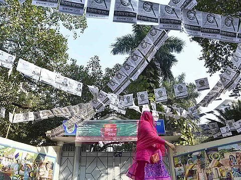 A Bangladeshi woman walks past a street adorned with election posters in Dhaka on December 28, 2018, ahead of the December 30 general election.