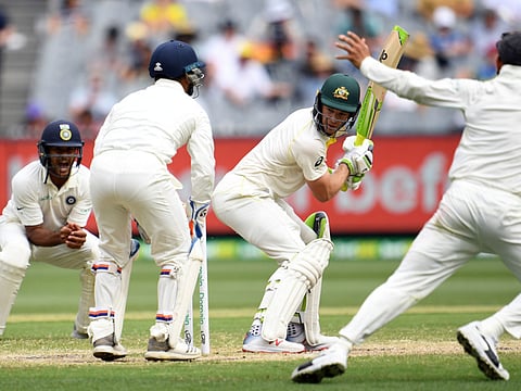 Australia's batsman Tim Paine (C) looks back after playing a shot as India's wicketkeeper Rishabh Pant (L) takes a successful catch during day four of the third cricket Test match between Australia and India in Melbourne on December 29, 2018.