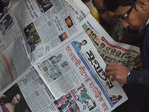 Bangladeshi people read a newspaper carrying headlines of the general election results in Dhaka on December 31, 2018