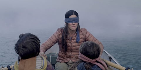 Sandra Bullock plays a woman trying to guide two small children (Julian Edwards, left, and Vivien Lyra Blair, right) to safety in the post-apocalyptic thriller “Bird Box.”