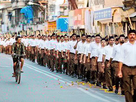 A man rides his bicycle past volunteers of the Hindu nationalist organisation Rashtriya Swayamsevak Sangh (RSS) taking part in Route March in Mumbai (File image)