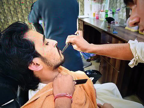 A Pakistani hairdresser styles the beard of a customer at a hair salon. For illustrative purposes only.