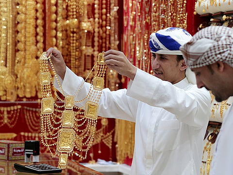 An employee shows a customer gold jewellery in a shop at the Gold Souq in Dubai