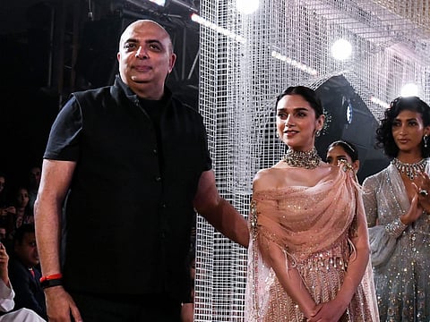 Bollywood actress Aditi Rao Hydari (R) presents a creation by Indian designer Tarun Tahiliani (L) during the India Couture Week 2018 in New Delhi on July 25, 2018.