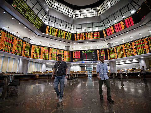 Investors walk in front of trading boards at a private stock market gallery in Kuala Lumpur, Malaysia. A jump in oil prices on Monday prompted global stocks to rise, as investors get a brief relief from being caught in between the tedious US-China trade disagreements.