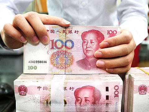 An employee counts 100-yuan notes at a bank in Nantong in China's eastern Jiangsu province. China’s policy makers acted to restrain a rally in the yuan by removing rules that made betting against the currency expensive.