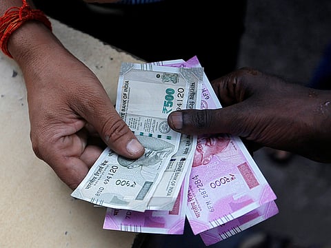 A customer hands Indian rupee notes to an attendant at a fuel station in Mumbai.