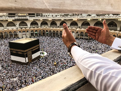 A muslim pilgrim prays while others circle the Kaaba and pray at the Grand mosque ahead of annual Haj