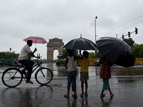 A file phot of Indian children with umbrellas standing near India Gate during heavy rain.