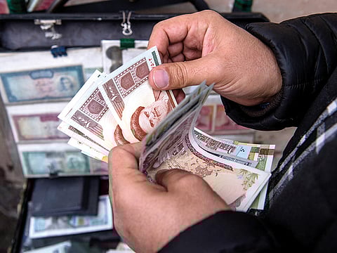 File photo: A currency trader counts Iranian rial banknotes at a money exchange market on Ferdowsi street in Tehran.