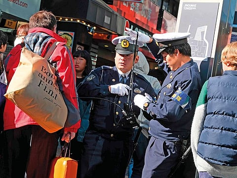 Policemen stand guard near Takeshita Street on Tuesday morning after a man drove into the crowd on New Year’s Eve in Tokyo’s fashion district of Harajuku.