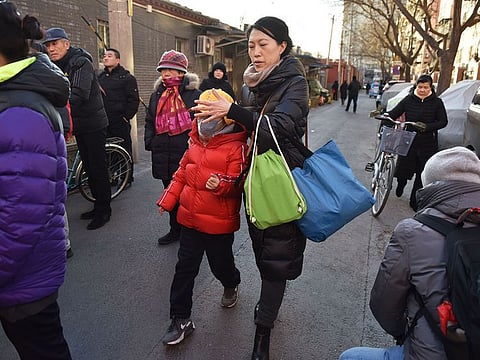 A relative escorts a child from an elementary school where an attack took place in Beijing on January 8, 2019.