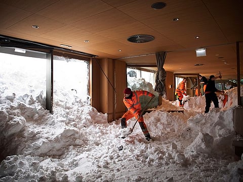 People clear snow from inside the Hotel Saentis in Schwaegalp, Switzerland, on Friday Jan. 11, 2019, after an avalanche.