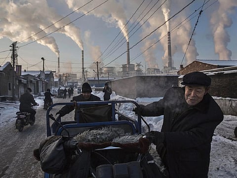 Smoke billowing as men pulled a tricycle in a neighbourhood near a coal-fired power plant in Shanxi Province.