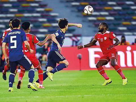 Oman player Saad Al Mukhaini (right) and Japan’s Nagatomo Yuto rush for the ball during their Group F match at the Zayed Sports City in Abu Dhabi on Sunday.