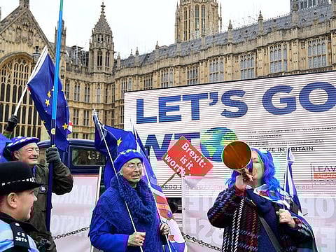 Anti-Brexit protesters stand next to a Pro-Brexit billboard outside the Houses of Parliament in London, Britain.