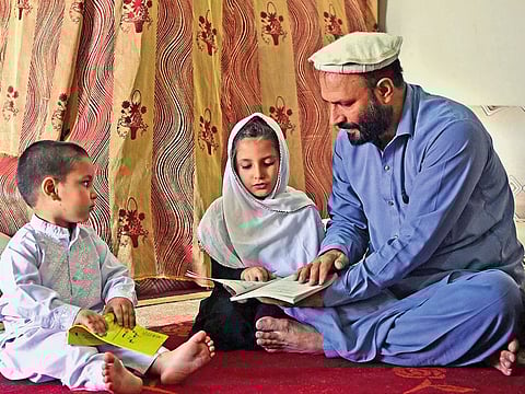 Afghan refugee Ashiqullah Jan teaches his children at his home in Peshawar.