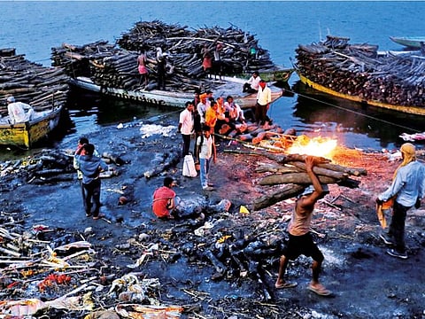 People watch as pyres burn at a cremation ground on the banks of the Ganges River in Varanasi, India.