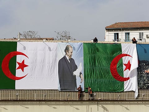 Algerian city employees install Algerian flags and President's Abdelaziz Bouteflika poster on the streets ahead of the Parliamentary election in Algiers in 2017