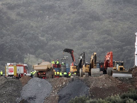 Drill and excavating machinery work on top of the mountain next to a deep borehole to reach a trapped 2-year-old boy.