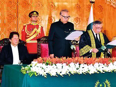 President Arif Alvi (centre) administers the oath to Asif Saeed Khan Khosa (right) as the new Supreme Court Chief Justice in Islamabad, as Prime Minister Imran Khan looks on.