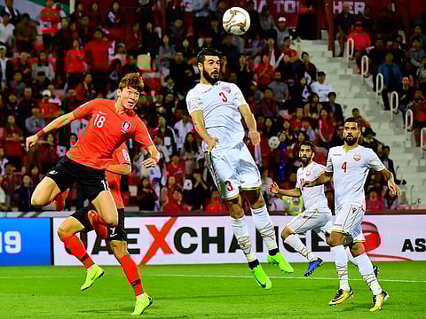 South Korea's forward Hwang Uijo (L) vies for the header with Bahrain's defender Waleed Al Hayam (C) during the 2019 AFC Asian Cup Round of 16 football match between South Korea and Bahrain at the Rashid Stadium in Dubai on January 22, 2019.