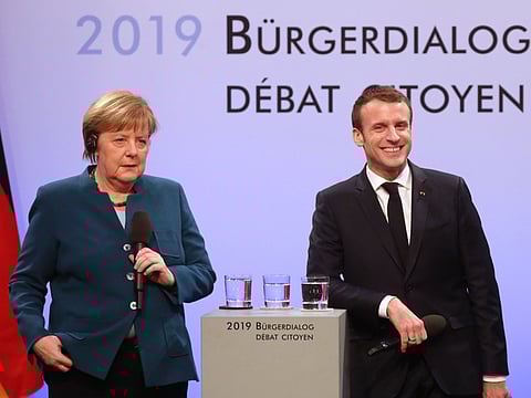 French President Emmanuel Macron (C, R) and German Chancellor Angela Merkel talk with German and French citizen after signing a French-German friendship treaty, on January 22, 2019 in the town hall of Aachen, western Germany.