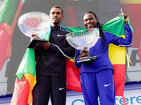 Getaneh Tamire Molla and Ruth Chepngetich, Men and Women winners of Standard Chartered Dubai Marathon, pose with trophies.
