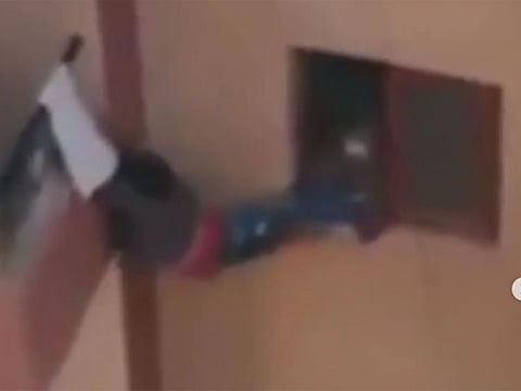Screenshot shows the child hanging between a window and a balcony of a high rise building