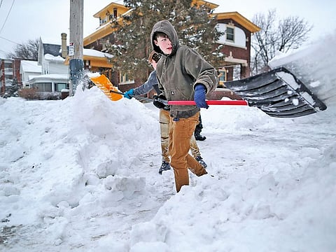 Nathan Tearman gets help from his brother James as they shovel the driveway of their home on Monday, after a winter snowstorm made its way through Janesville, Wisconsin