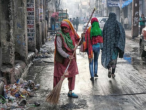 A street sweeper cleans a road during a morning of heavy air pollution at Chandni Chowk market in New Delhi.