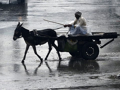 File photo: A man rides on his donkey cart across a flooded street during heavy rain in Lahore on January 21, 2019.