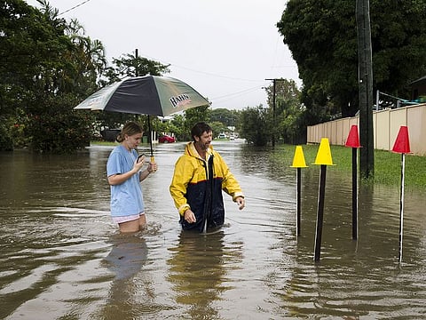 Local resident Paul Shafer and his daughter Lily stand in floodwaters near star pickets that show where the storm water cover has been removed in Hermit Park, Townsville, northern Queensland, Australia February 2, 2019.