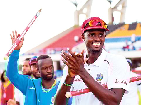 Jason Holder (R) of West Indies celebrates winning on day 3 of the 2nd Test between West Indies and England at Vivian Richards Cricket Stadium in North Sound, Antigua and Barbuda