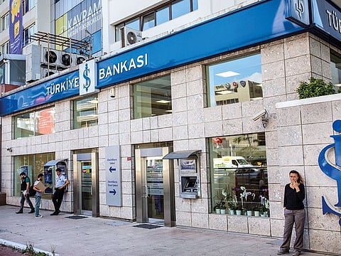 People stand outside a branch of Turkiye Is Bankasi AS, also known as Isbank, in the financial district of Istanbul, Turkey.