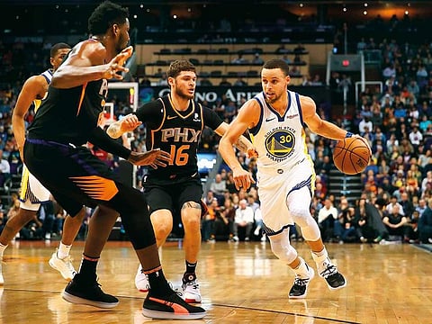 Stephen Curry #30 of the Golden State Warriors handles the ball against Deandre Ayton #22 and Tyler Johnson #16 of the Phoenix Suns during the first half of the NBA game at Talking Stick Resort Arena on February 08, 2019 in Phoenix, Arizona.