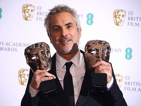 Director Alfonso Cuaron poses for photographers backstage with his Best Film and Best Director award for his film 'Roma' at the BAFTA awards in London, Sunday, Feb. 10, 2019.