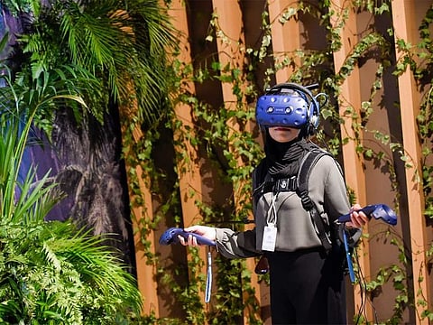 A visitor experiencing Tree virtual-reality project by New Reality that transforms you into a rainforest tree during the World Government Summit 2019.