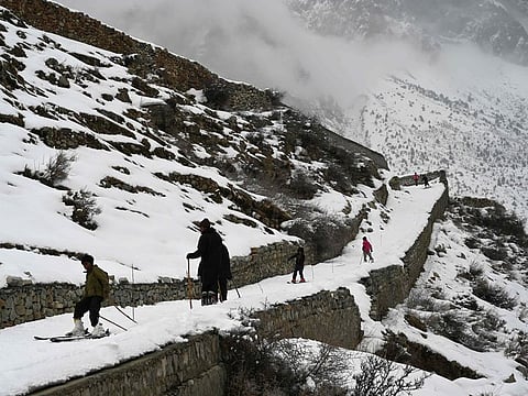 In this picture taken on January 30, 2019, Pakistani children ski on a snow-covered street -- with wooden sticks set up to practice the slalom -- next to their homes near the slopes where the CAS Karakoram International Alpine Ski Cup was taking place at the Pakistan Air Force-owned and operated Naltar Ski Resort, some 25km north of Gilgit in Pakistan's remote mountainous north.