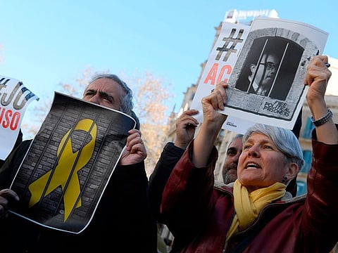 Protesters hold montages of jailed Catalan separatist politician Josep Rull and a yellow ribbon behind bars as staff of economy and agriculture ministries hold a ten-minute strike in Barcelona against the trial of former Catalan separatist leaders on February 12, 2019.