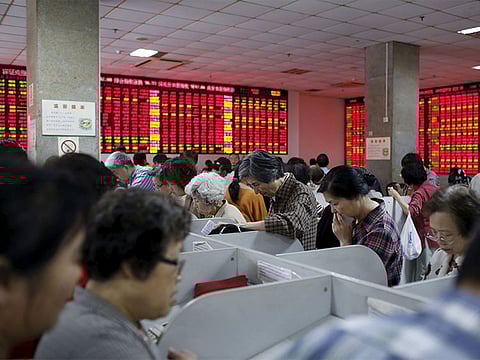 Investors look at computer screens showing stock information at a brokerage house in Shanghai.