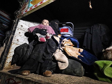 A woman wearing a niqab (full face veil) sits in the back of a truck carrying an infant and sitting next to pieces of luggage and a baby stroller, eastern Syrian Deir Ezzor province upon arriving with other fleeing families from remaining pockets held by Daesh.