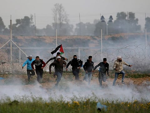 Palestinian demonstrators run away from Israeli fire and tear gas during a protest at the Israel-Gaza border fence, in the southern Gaza Strip, on February 15, 2019.