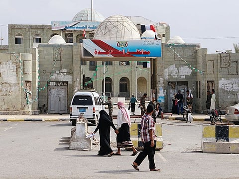 People walk past the headquarters of municipality of the Red Sea port city of Hodeidah