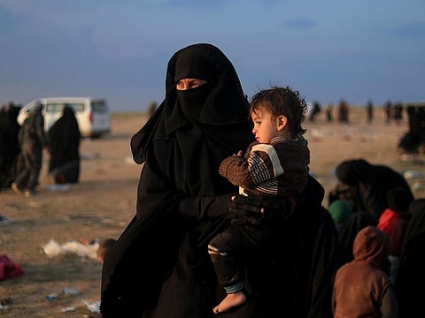 Women and children who fled the Islamic State (IS) group's last embattled holdout of Baghouz wait to be searched by US-backed Syrian Democratic Forces (SDF) fighters (